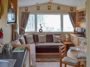 BactonにあるNorfolk Lavender Caravan - Sleeps 4 - WiFi and Sky TV Includedのリビングルーム(ソファ、テーブル付)