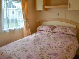 BactonにあるNorfolk Lavender Caravan - Sleeps 4 - WiFi and Sky TV Includedの窓付きの小さな部屋のベッド1台分です。