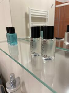 three bottles ofodorizers on a glass shelf in a bathroom at Castramajora Alloggi in Casalmaggiore