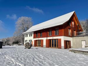 un grand bâtiment avec de la neige au sol dans l'établissement Wunderschönes Gästehaus mit grandioser Aussicht, à Gempen