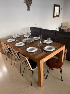 a wooden table with plates and wine glasses on it at Stunning Villa Amanecer in Corralejo