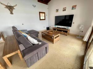 a living room with a couch and a flat screen tv at Stunning Villa Amanecer in Corralejo