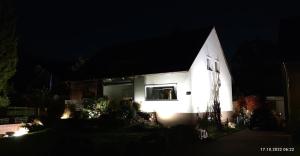 une église blanche avec des lumières sur son côté la nuit dans l'établissement Deisterquartier, Ferienwohnung am Naherholungsgebiet, à Barsinghausen