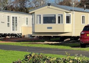 una casita amarilla estacionada junto a dos remolques blancos en Turnberry Holiday Home en Turnberry