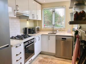a kitchen with white cabinets and a sink at Seakale Cottage in Rye Harbour