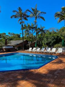 a swimming pool with lounge chairs and palm trees at Pousada Arraial do Ouro in Gaspar