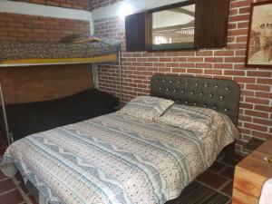 een slaapkamer met een bed in een bakstenen muur bij Villa Nico hospedaje campestre in Bochalema