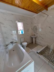 a bathroom with a tub and a toilet and a sink at Lion Rock View Guesthouse in Maseru