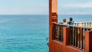 Dos mujeres sentadas en un balcón con vistas al océano en Candia Park Village, en Agios Nikolaos