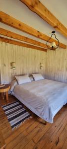 Cama en habitación con paredes de madera y techo en La Pilarica Lodge en Cholila