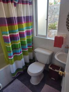 a bathroom with a toilet and a rainbow shower curtain at Casa Mamalluca in Vicuña