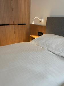 a bedroom with a white bed with a dresser and a lamp at Luxury by The Lake Ap 25 in Sibiu