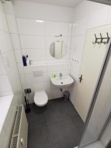 biała łazienka z toaletą i umywalką w obiekcie Ferdimesse Apartments 2 w Kolonii