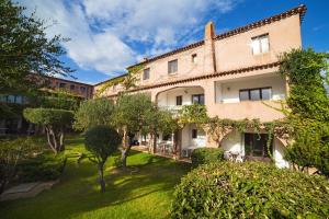 une vue sur l'extérieur d'un bâtiment avec des arbres et des buissons dans l'établissement Residence La Rosa, à Porto San Paolo