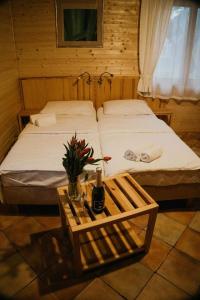 Un dormitorio con 2 camas y una mesa con una botella de vino. en Daglezjowy Dwór en Osiek