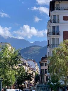 a city street with buildings and a mountain in the background at Une escapade au cœur d'Annecy in Annecy