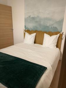 a bed with white pillows and a green blanket at Une escapade au cœur d'Annecy in Annecy