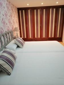 - une chambre avec un grand lit blanc et des oreillers dans l'établissement Piso Céntrico Vigo 6 pax Lola, à Vigo