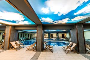 a pool with chairs and a mural of a sky at Gardenia Park Hotel in Bansko