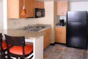 a kitchen with a black refrigerator and a sink at Sonesta ES Suites Dallas Central Expressway in Dallas