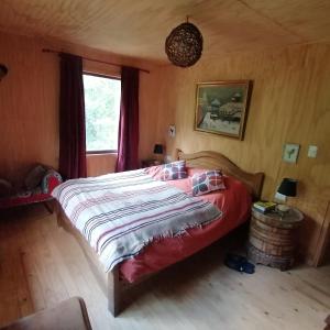 a bedroom with a large bed with a red comforter at Cabaña La Chaura Conguillío in Melipeuco