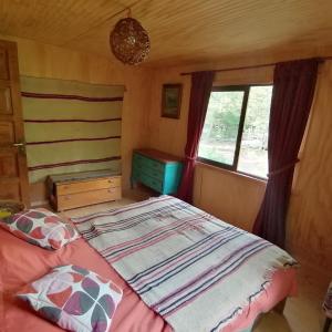 1 dormitorio con cama y ventana en Cabaña La Chaura Conguillío en Melipeuco