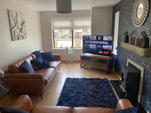 een woonkamer met een bank en een flatscreen-tv bij Derryree House in Lisnaskea