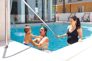 un uomo e una donna che giocano in piscina di Hotel Tiffany & Resort a Cesenatico