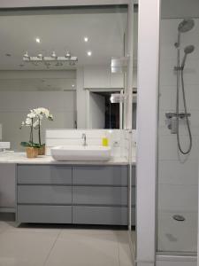 a white bathroom with a sink and a shower at Amber Hostel Szlak in Krakow
