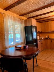 - une cuisine avec une table en bois et un réfrigérateur noir dans l'établissement Cabană la poalele munților cu ciubăr, à Jieţ