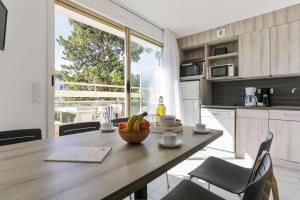 a kitchen with a table with a bowl of fruit on it at Résidence Pierre & Vacances La Corniche d'or in Boulouris-sur-Mer