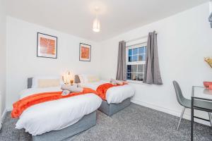 two beds in a bedroom with a desk and a window at Hereford Road Shrewsbury Cottage in Shrewsbury