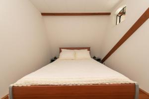 een kleine slaapkamer met een bed met witte lakens bij Atelier / Guesthouse Arriën - De Studio van Slim in Arriën