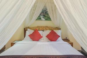 a bedroom with a white bed with red pillows at Ubud Kerta City Hotel in Ubud