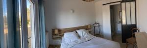 a bedroom with a bed with white sheets and a window at La Rolande in Aix-en-Provence