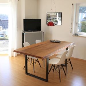 uma mesa de jantar com cadeiras brancas e uma televisão em apartment-S Sonnenrain em Lörrach