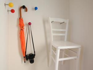 um guarda-chuva laranja pendurado numa parede ao lado de uma cadeira branca em apartment-S Sonnenrain em Lörrach