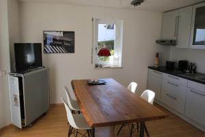 eine Küche mit einem Holztisch und weißen Stühlen in der Unterkunft apartment-S Sonnenrain in Lörrach