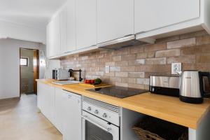 a kitchen with white appliances and a brick wall at Carvoeira Surf & Family Villa in Carvoeira