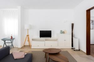 a living room with a tv on a white cabinet at Carvoeira Surf & Family Villa in Carvoeira