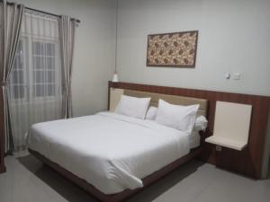 um quarto com uma grande cama branca e uma janela em Griya Sambilegi em Yogyakarta