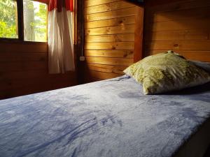 Cama con almohada en habitación con ventana en Refugio del Bosque en El Bolsón