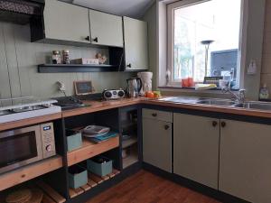 a kitchen with a sink and a microwave at B&B 't Gezellig Huizeke in Zoersel