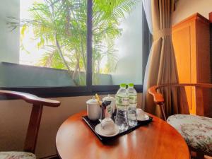 a table with a tray with cups and bottles on it at LEHA Saigon Hotel Airport in Ho Chi Minh City