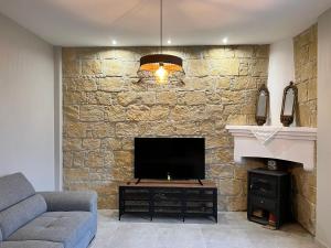 a living room with a tv and a stone wall at Eftis - Renovated Traditional House in Omodos
