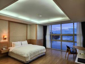 a bedroom with a large bed and a large window at Benikea Hotel Yeosu in Yeosu