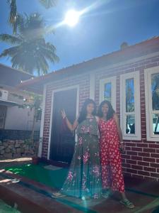 two women posing for a picture in front of a house at Gruham Cottage Malpe in Malpe