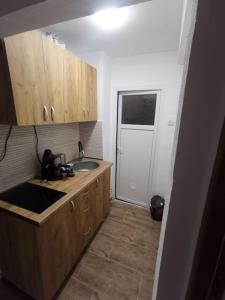 uma cozinha com armários de madeira, um lavatório e uma porta em Very good location em Hunedoara