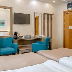 Habitación de hotel con 2 camas y 2 sillas azules en Studio u Hotelu Alibi Inn, en Zlatibor