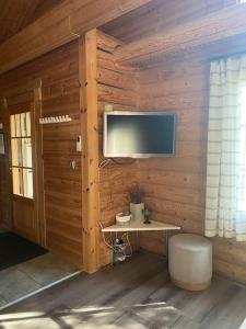 Habitación con pared de madera, TV y taburete. en Latvahonka Cottage en Jämsä